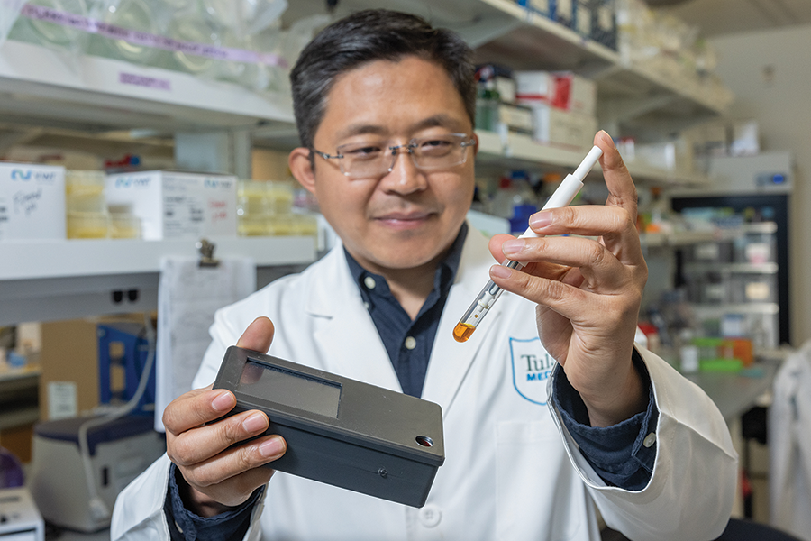 A scientist in a lab holds a small testing device.