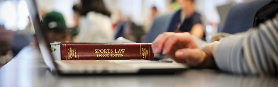 Sports Law textbook on top of a laptop.