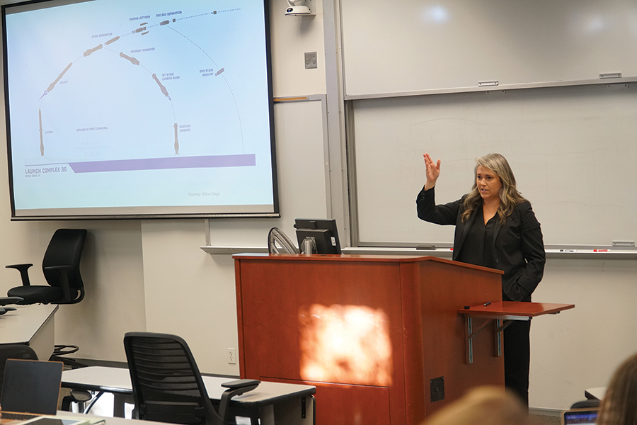 A professor gives a lecture at the front of a class.