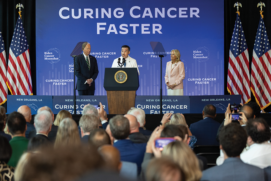 Dr. Quincy Brown stands on stage with former President Joe Biden and former First Lady Dr. Jill Biden as they celebrate the grant to support the MagiScan cancer moonshot program.