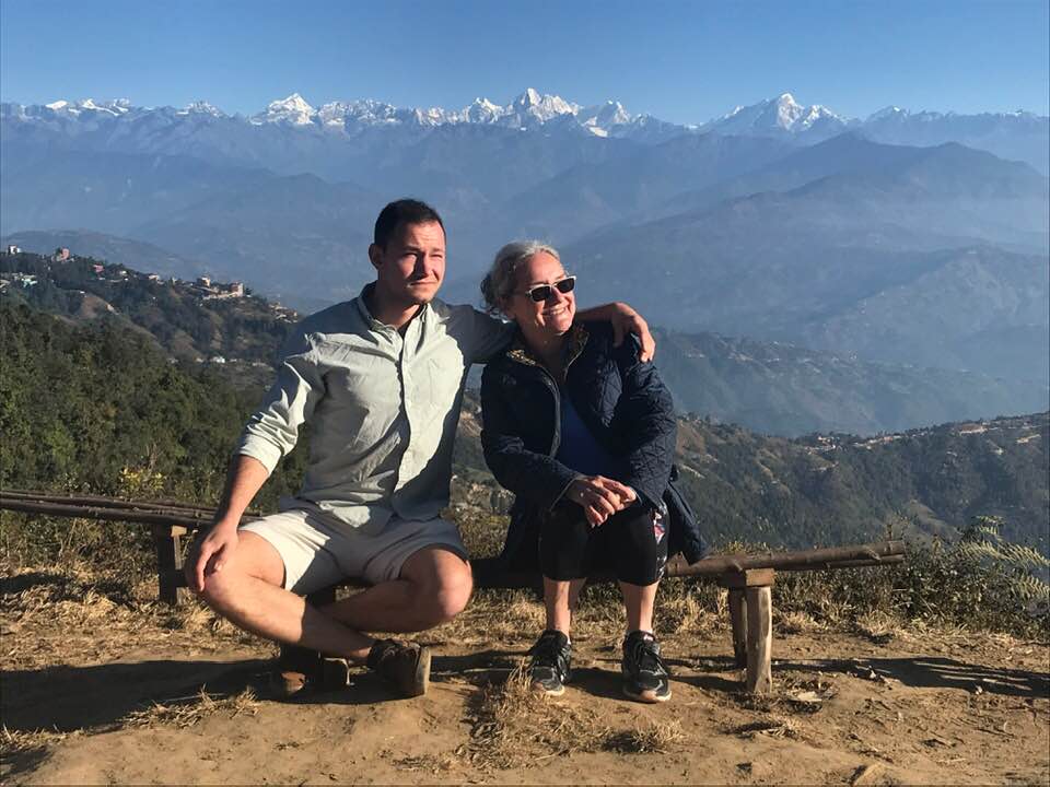 Nancy Mock with her son, Alex, in Nepal, mountains in the background, sun shining on them. 