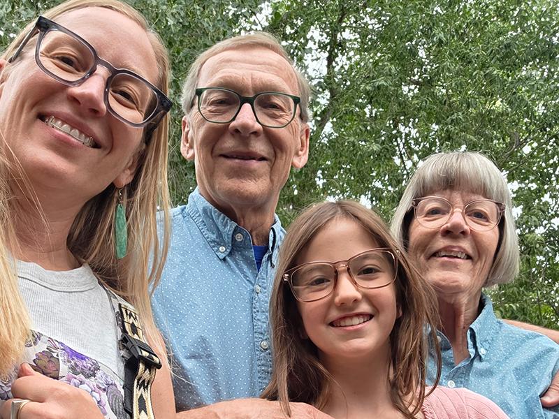 smiling, (woman, elderly couple, girl) poses outdoors.