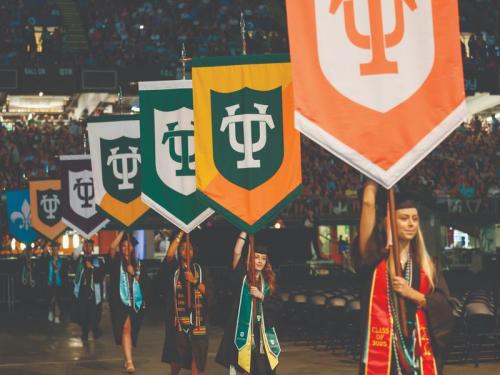 Graduating students carrying banners.