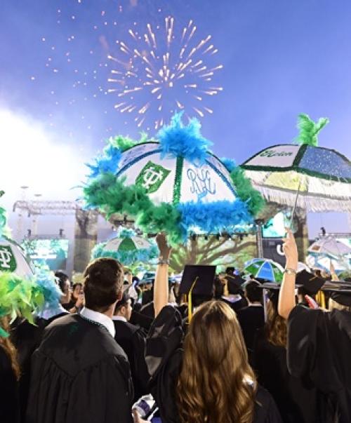 Two graduates at commencement watching fireworks.