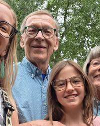 smiling, (woman, elderly couple, girl) poses outdoors.