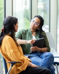 Photograph: Woman in olive shirt comforts another in a yellow sweater, both seated and talking.